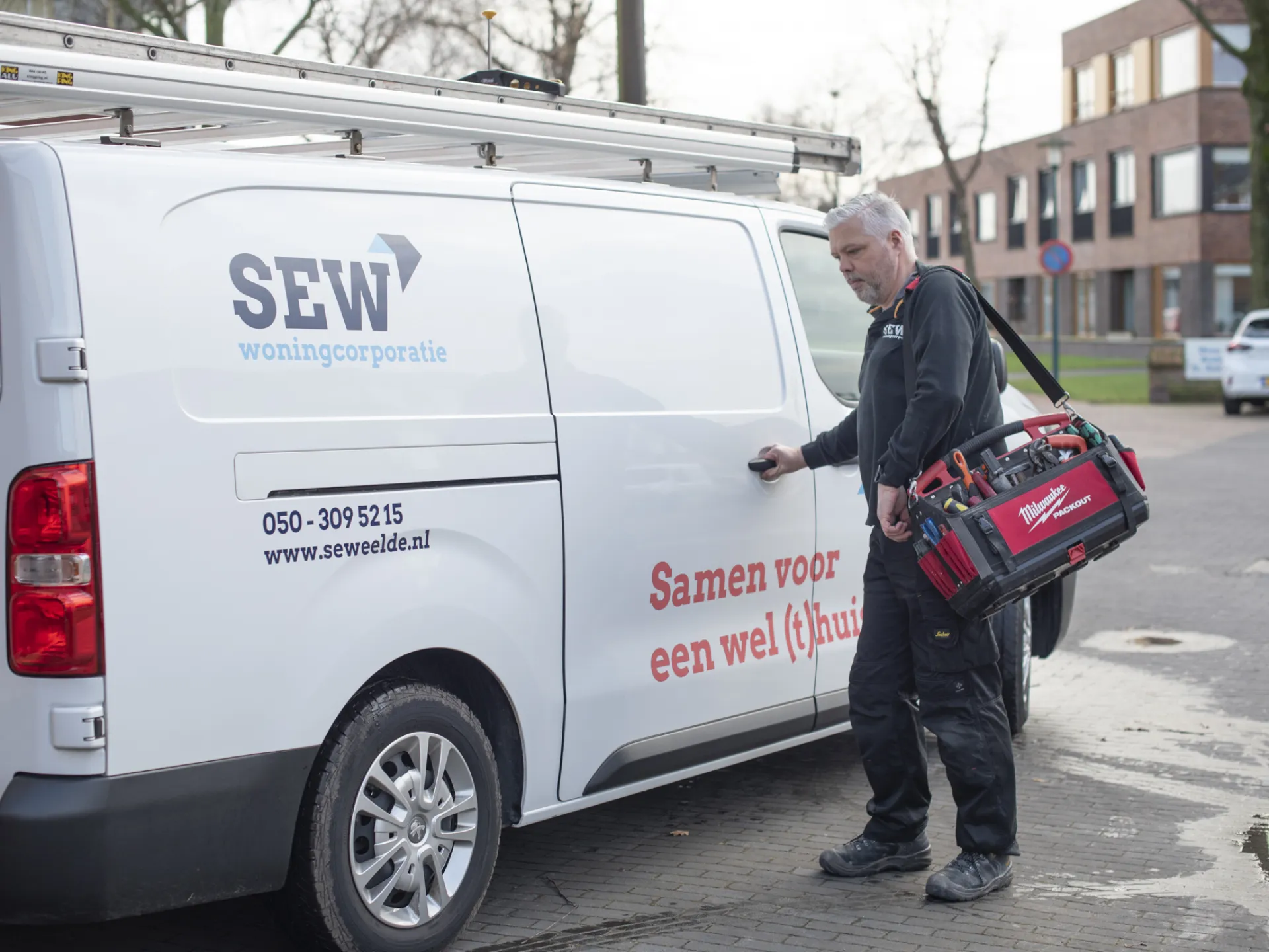 Monteur met gereedschapstas bij een servicebus.