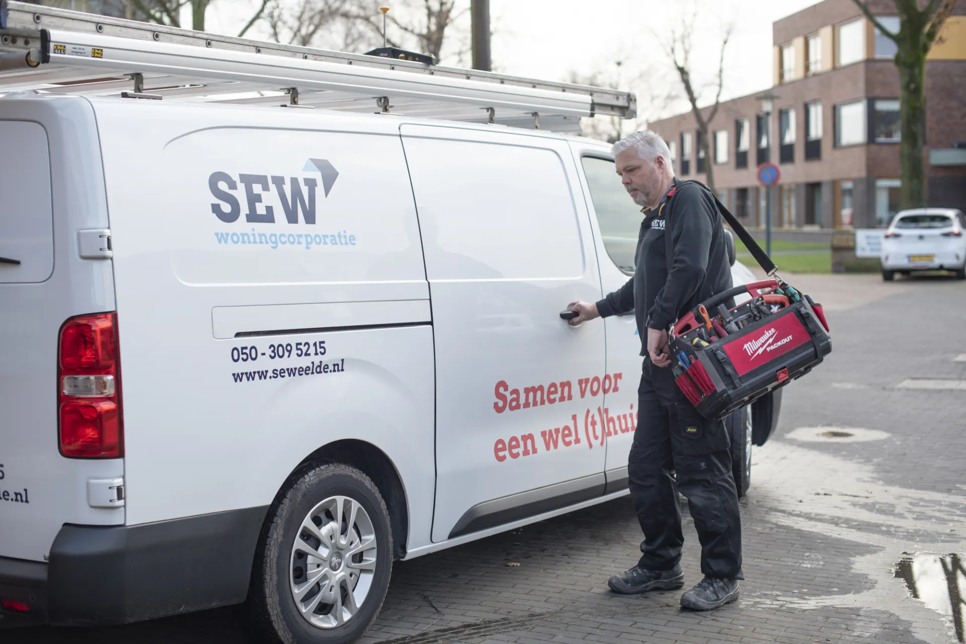 Monteur met gereedschapstas bij een servicebus.